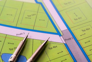 Eine ausgebreitete Planzeichnung auf der ein Zirkel liegt.