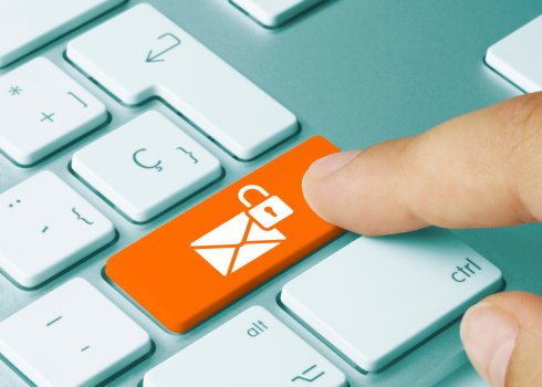 Verschlüsselte E-Mails Computer-Tastatur bei der auf der orangenen rechten Umschalttaste ein weißes Briefsymbol mit geschlossenem Schloss-Symbol zu sehen ist; Ein Zeigefinger drückt diese Taste