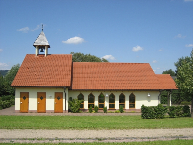 Seitliche Ansicht der Trauerhalle am neuen Friedhof im Ortsteil Altenhaßlau umgeben von Rasenflächen und Heckenbepflanzung