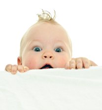 clamber Baby schaut mit großen Augen hinter einem weißen Handtuch hervor