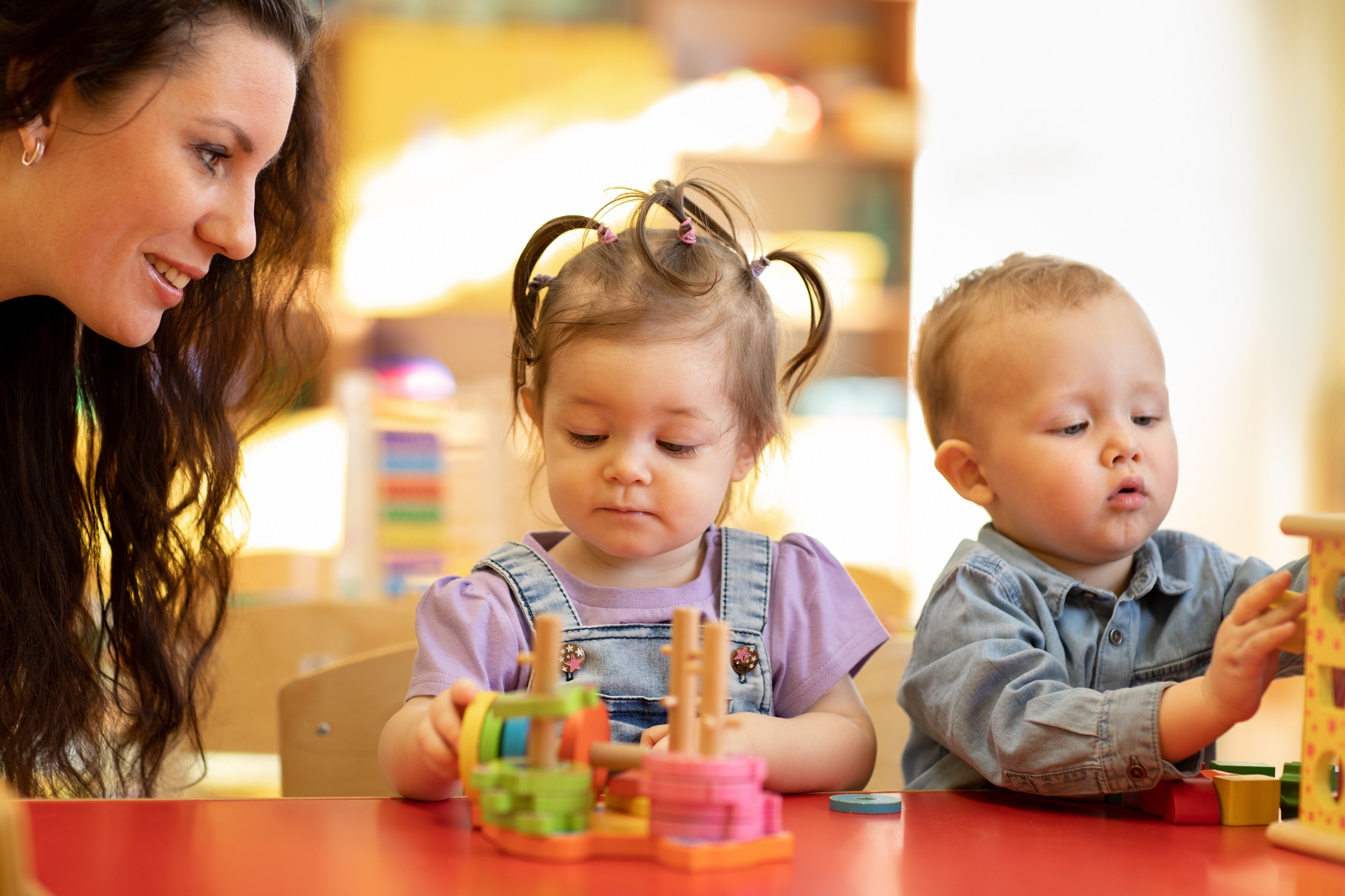 Betreuerin begleitet zwei Kleinkinder beim Spielen
