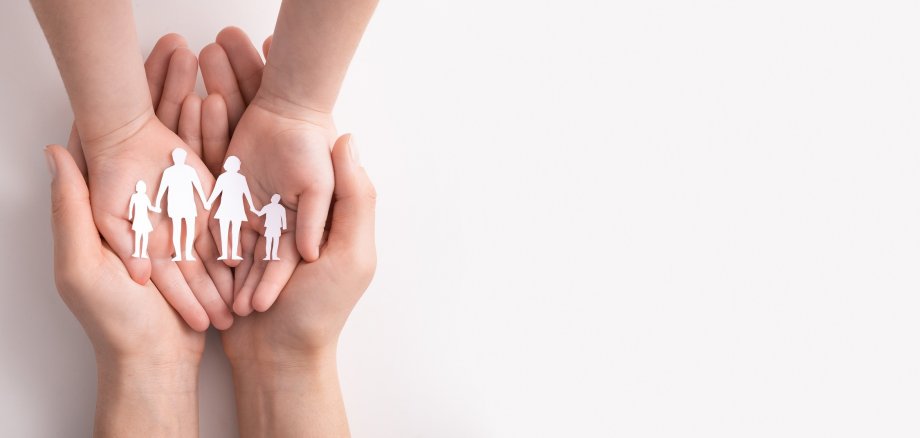 Family care concept. Hands with paper silhouette on table.