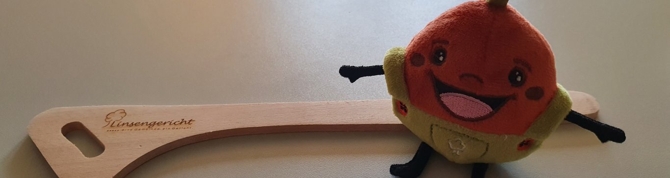 Das Linsi-Maskottchen steht vor dem Linsengericht-Kochlöffel