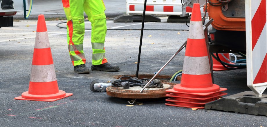 Kanalarbeiter sichern einen Schacht