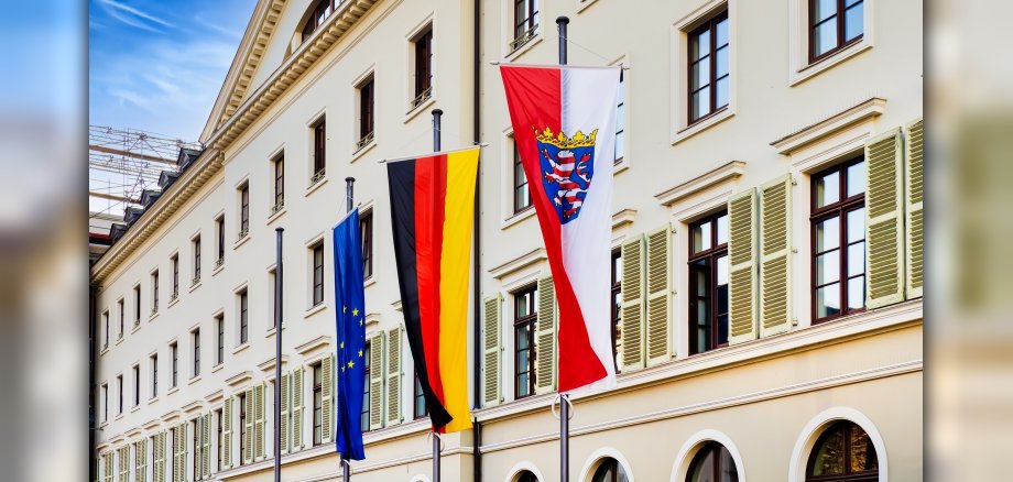 Bundes-, Landes- und Europaflagge vor dem Gebäude des hessischen Landtages