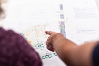 Mitarbeiter deutet mit dem Finger auf eine Planskizze, um seine Kollegin auf etwas aufmerksam zu machen