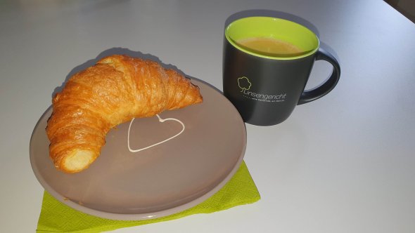 Die Linsengericht-Tasse mit Gemeindelogo, daneben ein Teiller mit einem Croissant