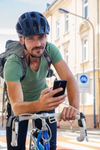 Radfahrer mit Handy schaut in die Kamera