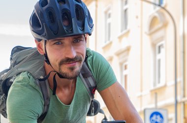 Radfahrer mit Handy schaut in die Kamera