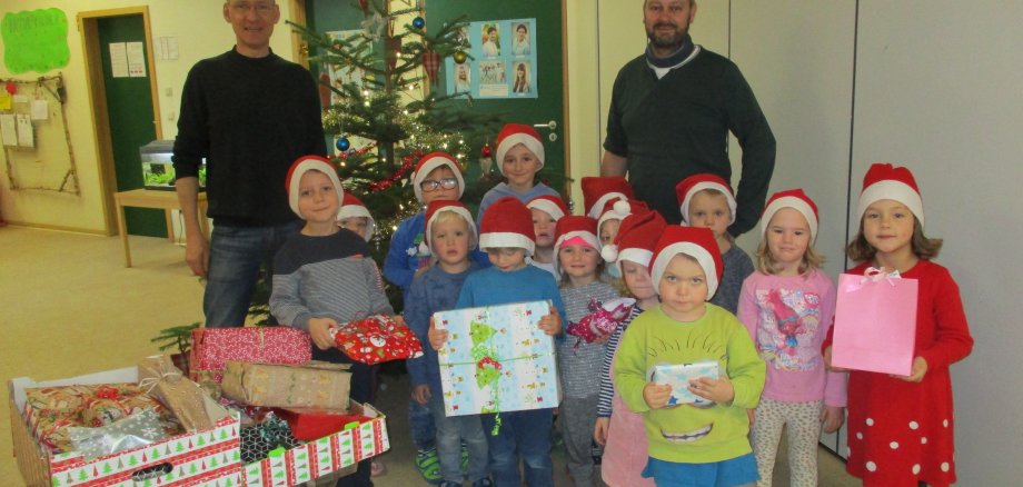 Kinder der Kindertagesstätte Wirbelwinde halten Weihnachtpäckchen in den Händen