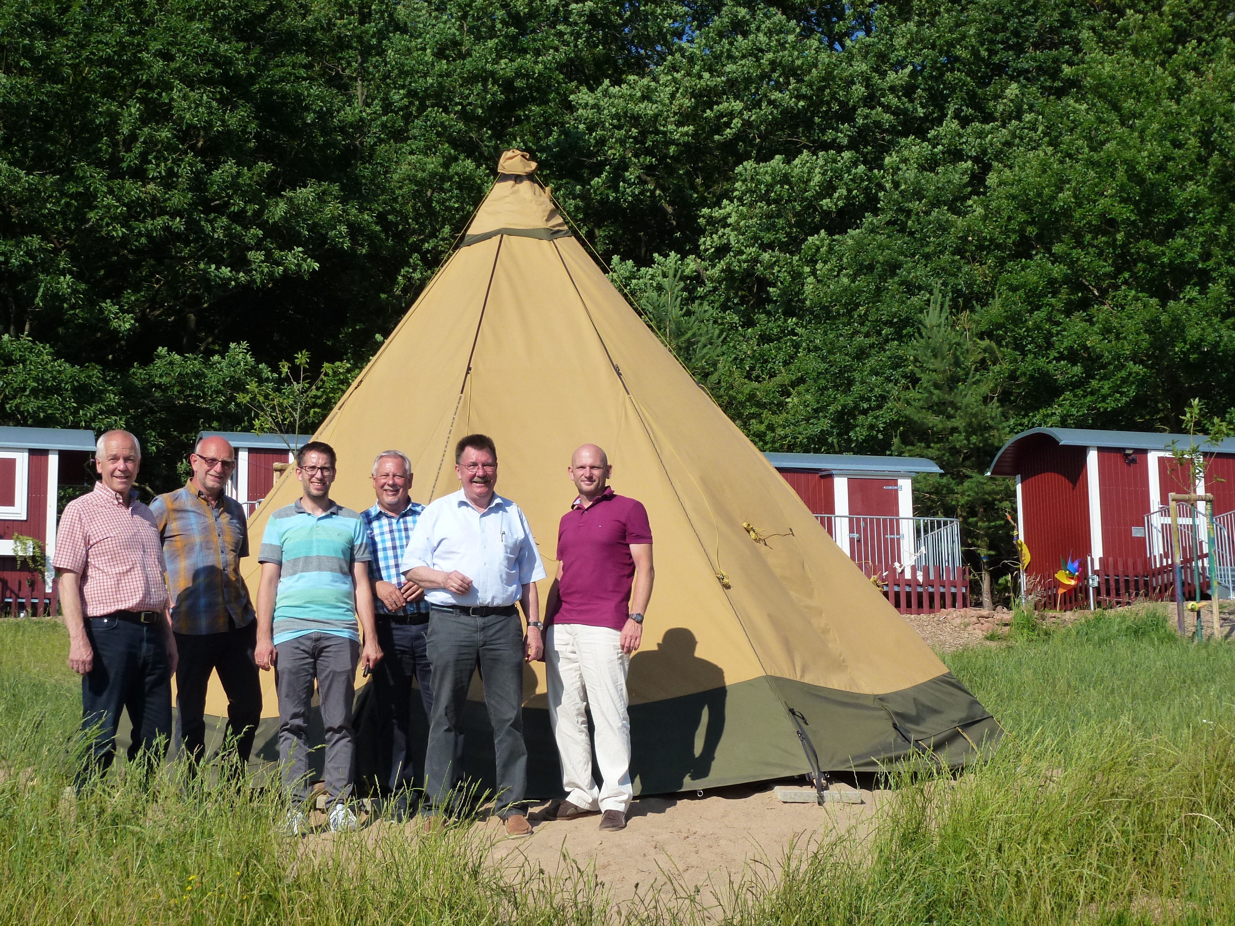 Mandatsträger und Mitarbeiter der Gemeinde stehen vor dem Tipi auf dem Gelände des Waldkindergartens.