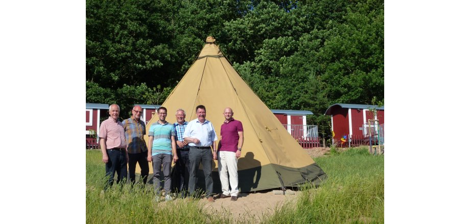 Mandatsträger und Mitarbeiter der Gemeinde stehen vor dem Tipi auf dem Gelände des Waldkindergartens.