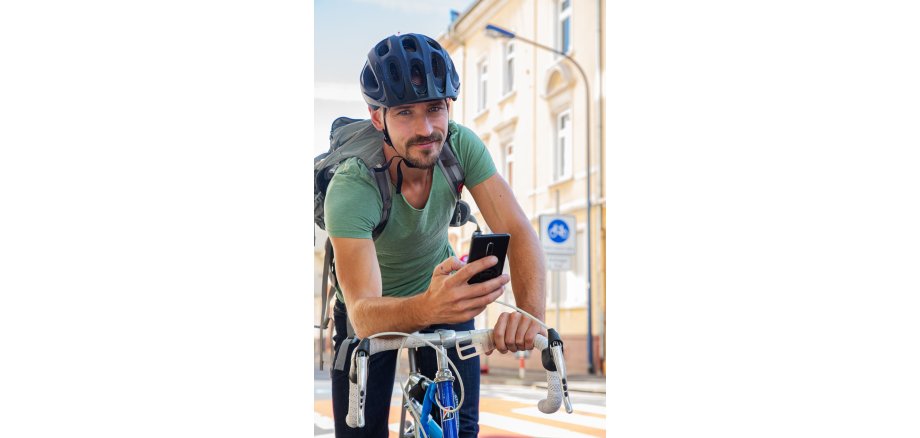 Radfahrer mit Handy schaut in die Kamera